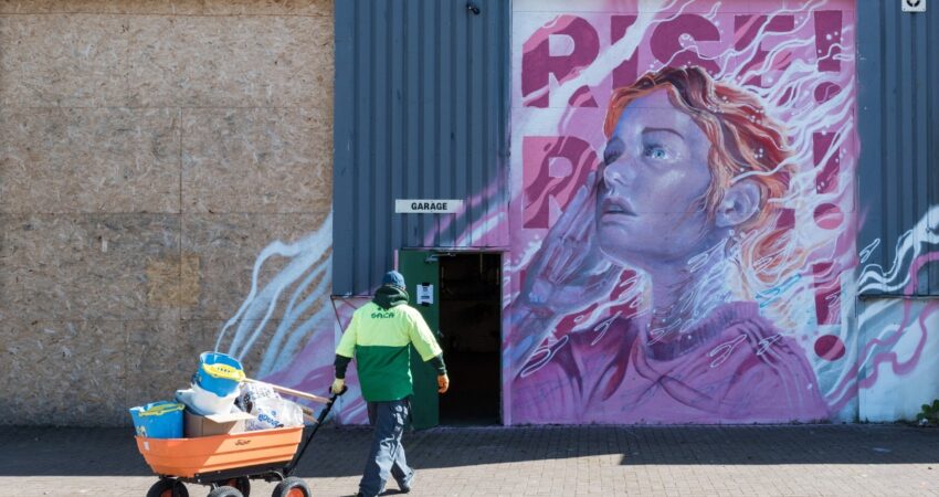 Volunteer at the Paper Factory in front of mural